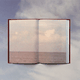 A book opened to an image of an open horizon, set against a blue sky