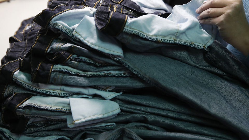 A hand sorts through a stack of jeans.