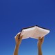 Young woman holding book up in air, low angle view