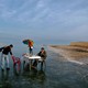 Three men set up a dining table in the middle of frozen water.