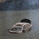 An abandoned vehicle floats in floodwater.