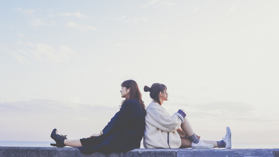 Two people sitting back to back