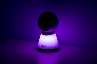 The VTech VM5254 baby monitor's camera, pictured in a dark setting with the base of the camera glowing bright purple.