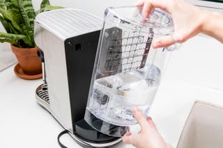 A person removing the water tank from the back of the Bambino espresso machine.