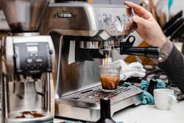 A person pulling an espresso shot with an espresso machine.