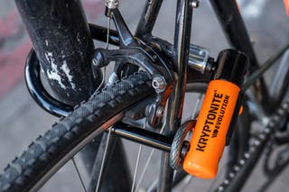 A close-up of a wheel and post locked using the Kryptonite New-U Evolution Mini-7 u-lock.