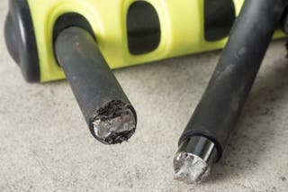 A close-up of the metal of a black and yellow bike lock cut through with a bolt cutter.