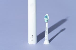 A Philips Sonicare 4100 handle, with a detached plaque control style brush head standing alongside it, both shown in white.