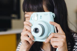 A person using the Fujifilm Instax Mini 9 instant camera.