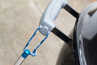 A close-up of a tool hook on a charcoal grill.