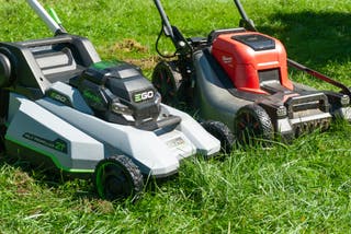 Two lawn mowers resting in the grass.