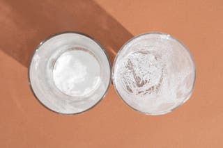 Two cups with residue from two different powder laundry detergents that we tested for solubility. The cup on the right has much less powder residue left over.