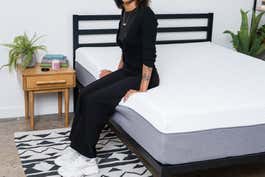 A mattress tester sitting on the edge of the Novilla Bliss Memory Foam Mattress.