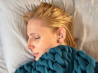 Our tester wearing the A20 earbud while laying in a bed with their eyes closed.