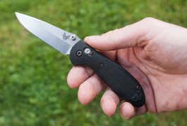 A hand holding the Benchmade Mini Griptilian pocket knife.