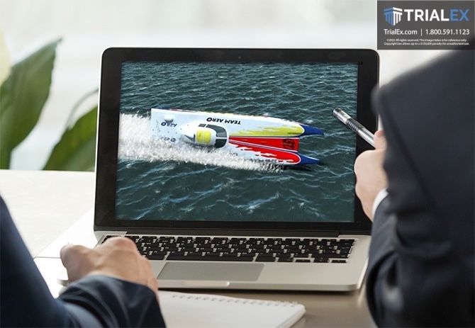 Laptop with screen displaying a watercraft sideways in a body of water being reviewed by a trial consultant and attorney.