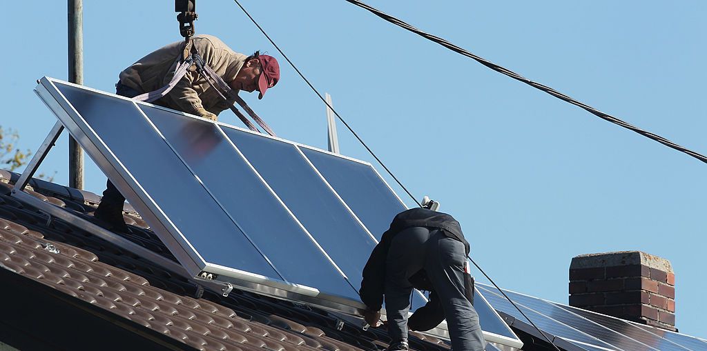 STARNBERG, GERMANY - OCTOBER 15:  Workers install solar power modules for producing heat on the roof of a house on October 15, 2011 in Wessling, Germany. Germany has and is continuing to invest heavily in solar energy, both in the public and private sectors. The German government introduced a feed-in tariff with its Renewable Energy Act in 2000 that guarantees homeowners a minimum rate for selling electricity from renewable energy sources into the nation's electricity grid.  (Photo by Alexandra Beier/Getty Images)