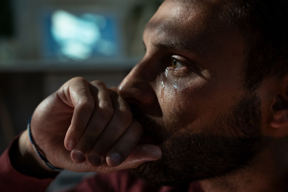 Trauriger Mann weint nachts im Wohnzimmer. Konzept von Depression.