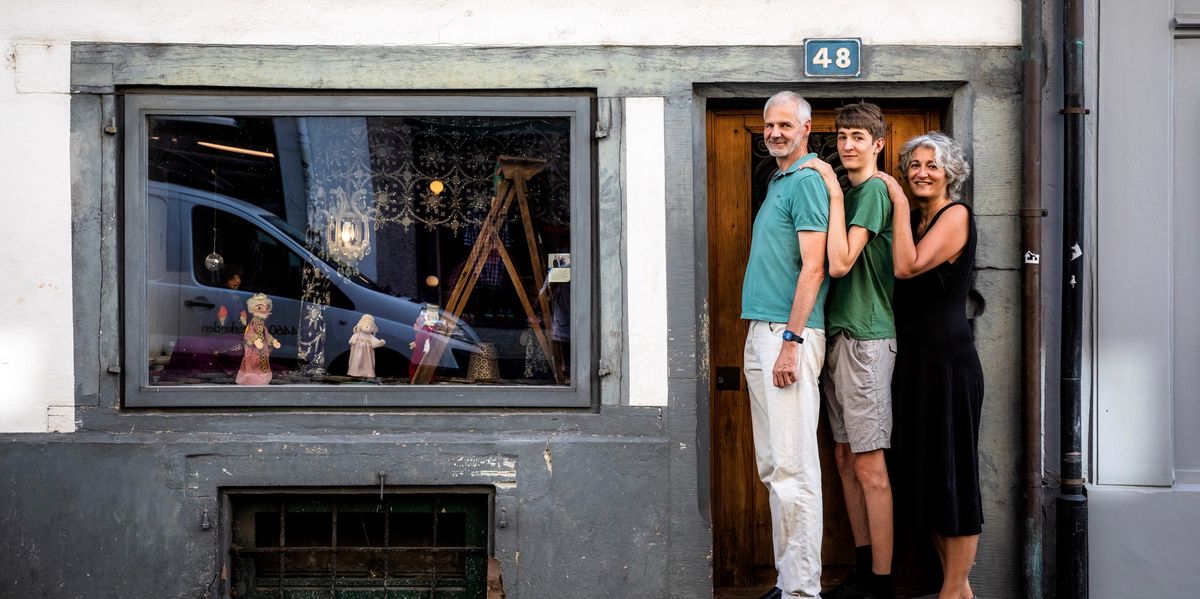 Geraldine Friedrich und ihre Familie, alle gross, stehen nebeneinander vor einem kleinen Türrahmen auf der Rebgasse und Vogelsangstrasse in Basel. Foto vom 6.8.24 von Kostas Maros.