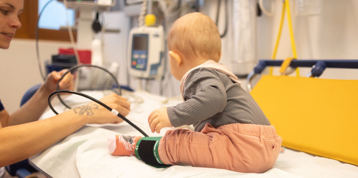 Ein Kleinkind sitzt auf einer Untersuchungsliege im Universitäts-Kinderspital beider Basel (UKBB). Eine Ärztin oder Pflegerin hält ein medizinisches Gerät.