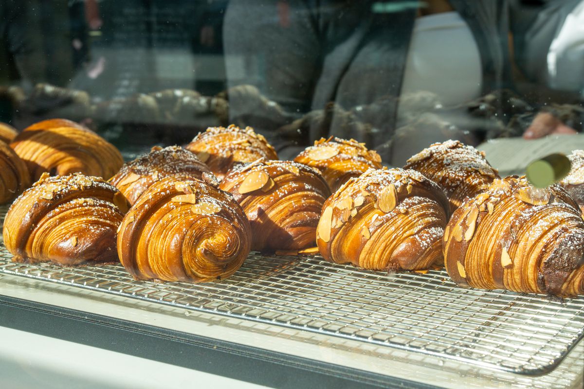 Almond croissants on a metal rack with a glass display.