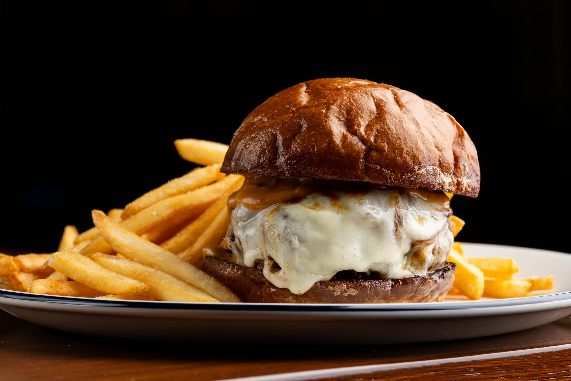 Dry-aged burger with provolone, grilled onions, pickled jalapenos, and French fries at Camelia