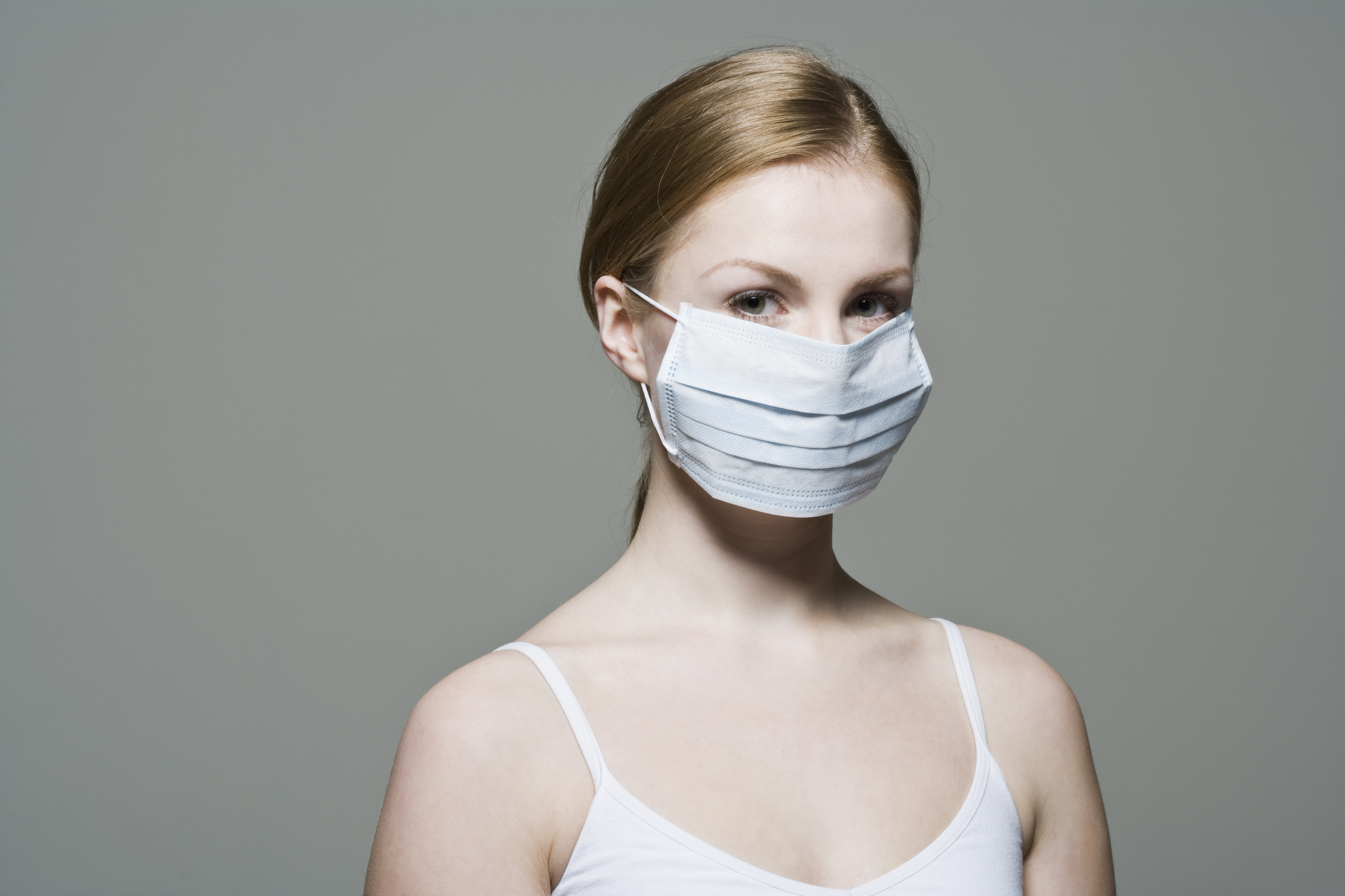 A woman wears a disposable dust mask.