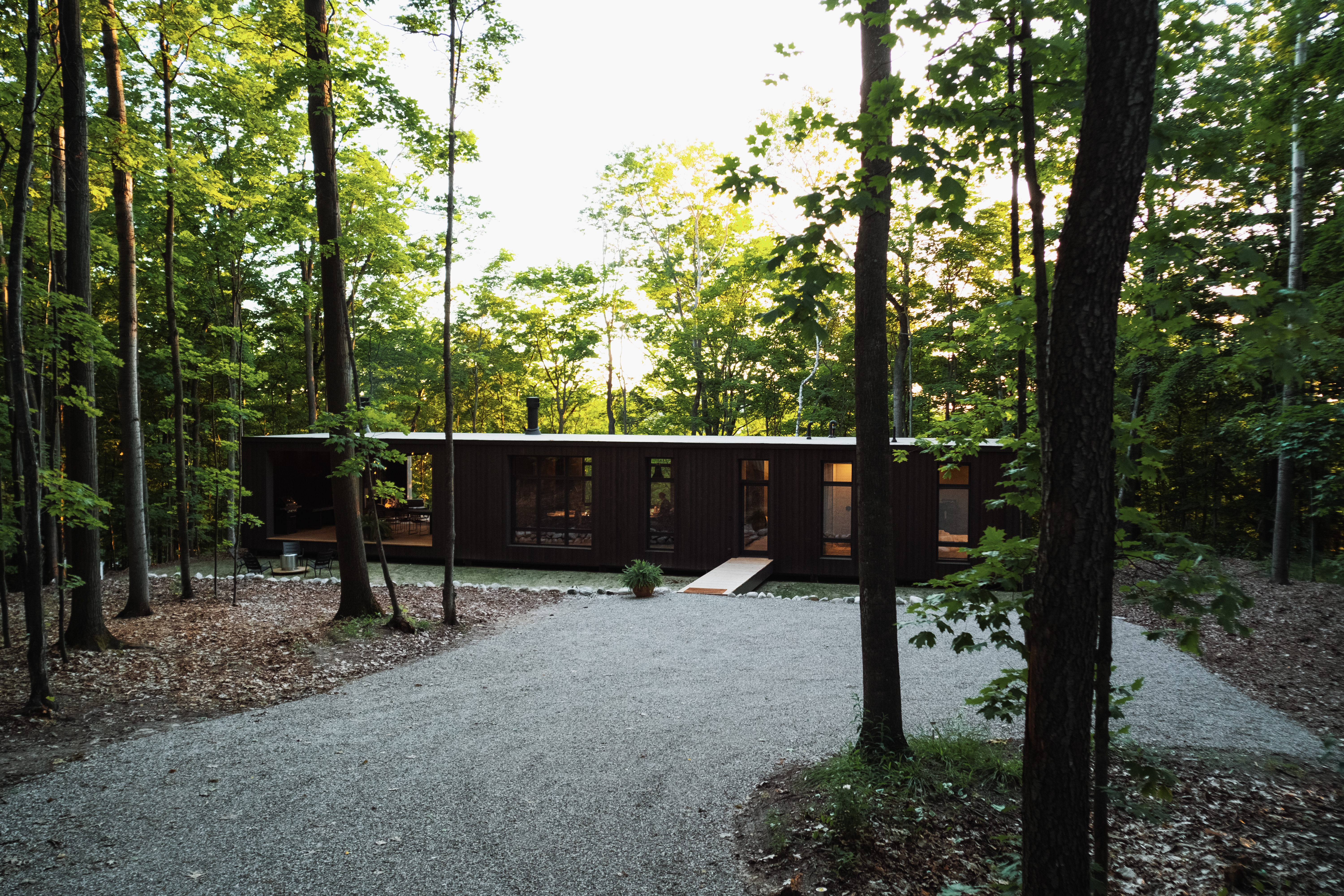 Single story prefab home surrounded by trees.