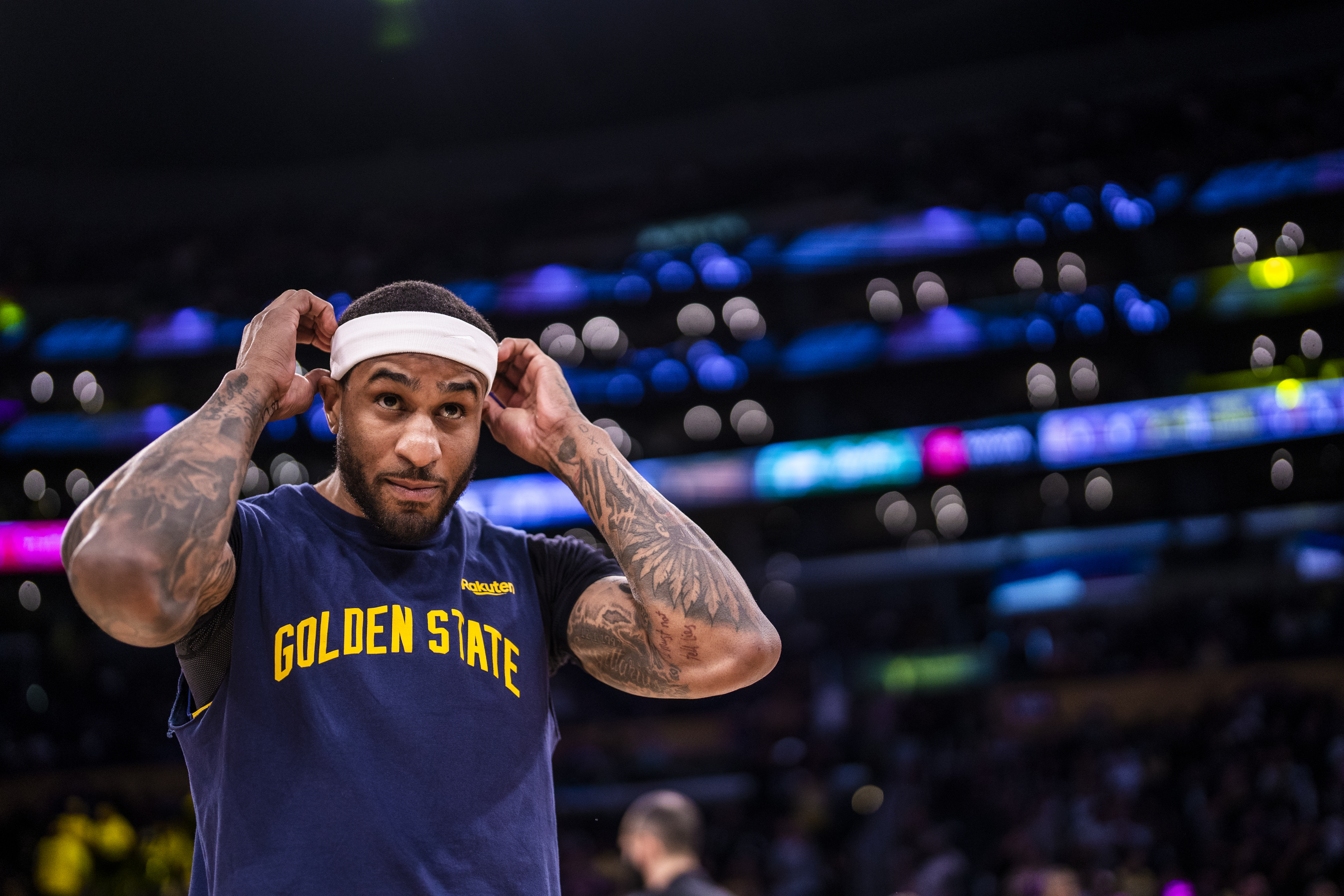 Gary Payton II adjusts his headband before the game against the Los Angeles Lakers at Crypto.Com Arena in Los Angeles. He is wearing a navy blue “Golden State” warmup shirt.