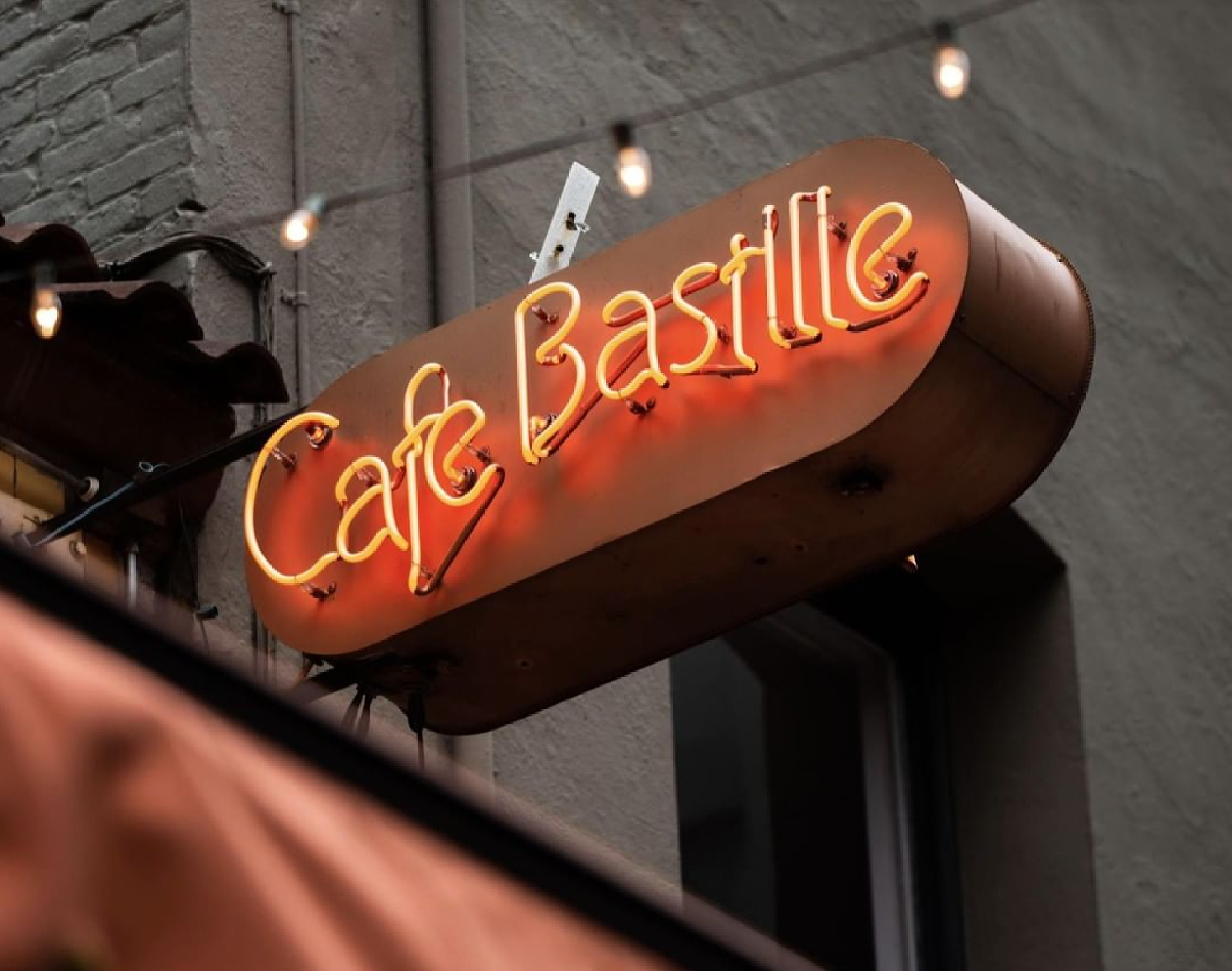 A neon orange sign that reads “Cafe Bastille.”