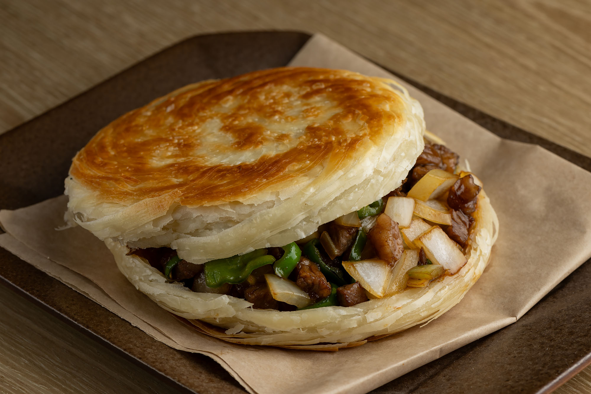 Wagyu beef Chinese burger served under brown parchment paper on a square plate at Good Alley.