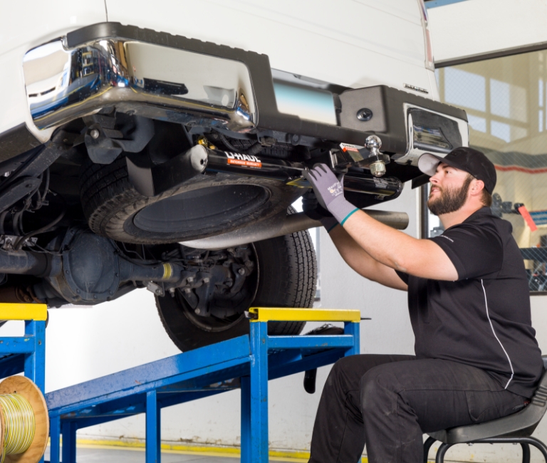 A mechanic installing a trailer hitch on a pick-up truck