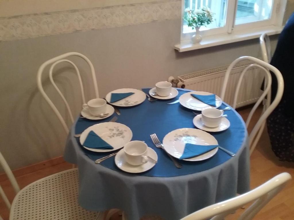 une table bleue avec plaques et argenterie dans l'établissement Poska Villa Guesthouse, à Tallinn