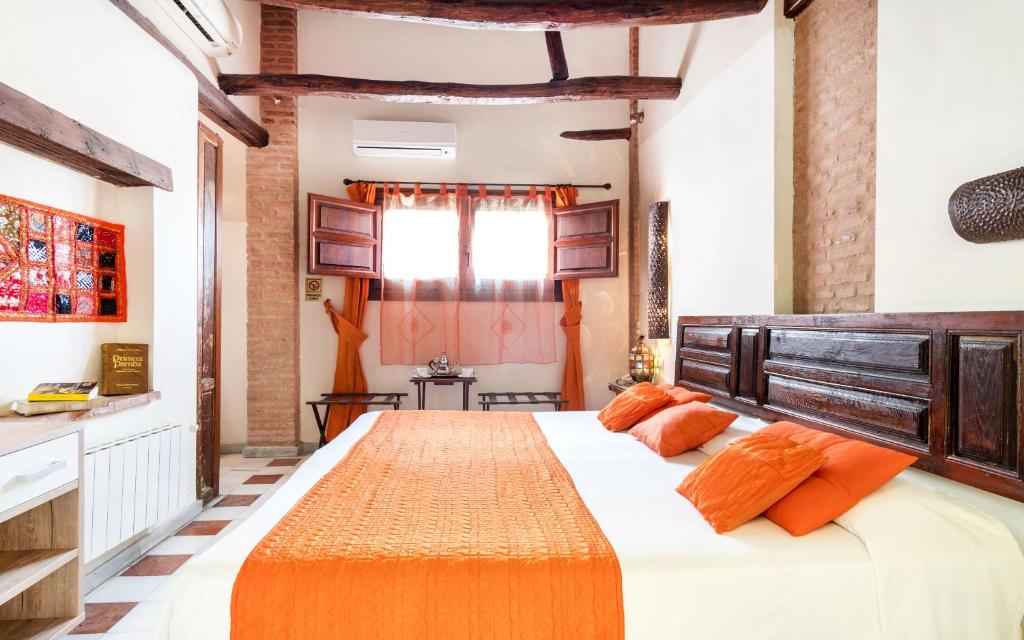 1 dormitorio con 1 cama grande con almohadas de color naranja en Casa de Federico Boutique, en Granada