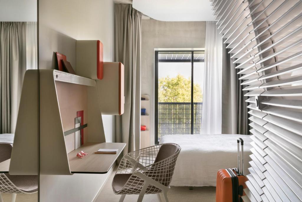 a hotel room with a bed and chairs and a staircase at Okko Hotels Strasbourg Centre in Strasbourg