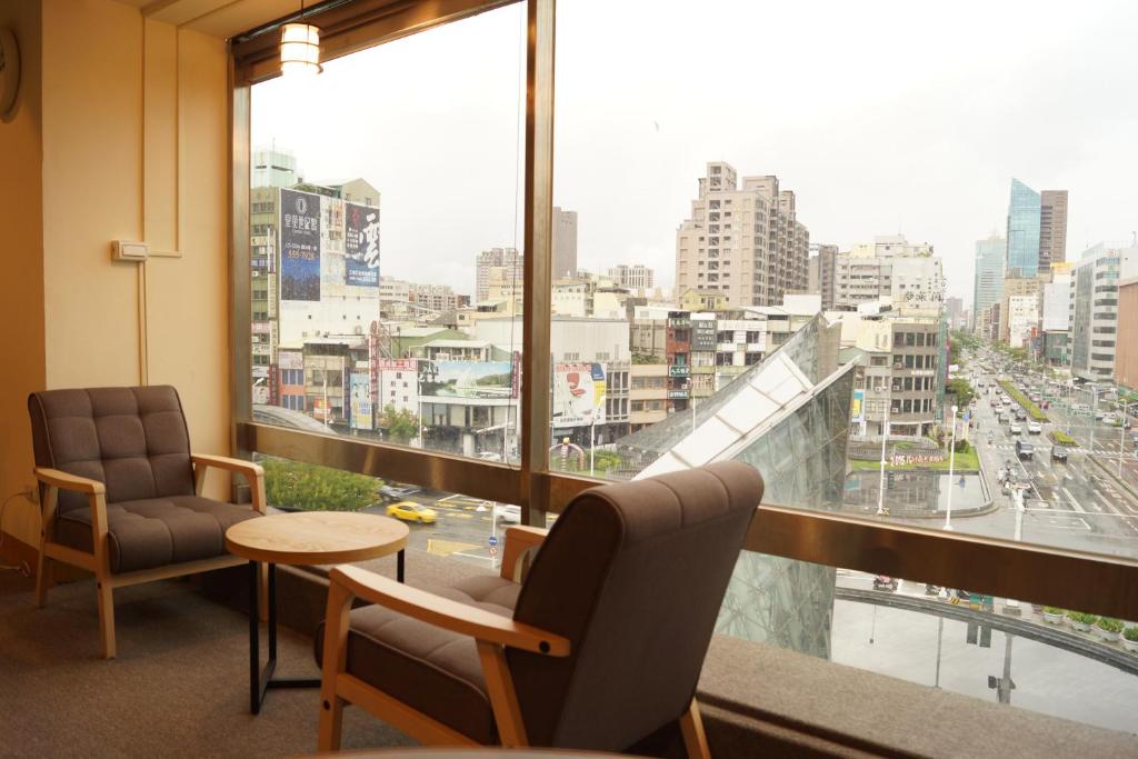 een kamer met 2 stoelen, een tafel en een groot raam bij Trip GG Hostel in Kaohsiung