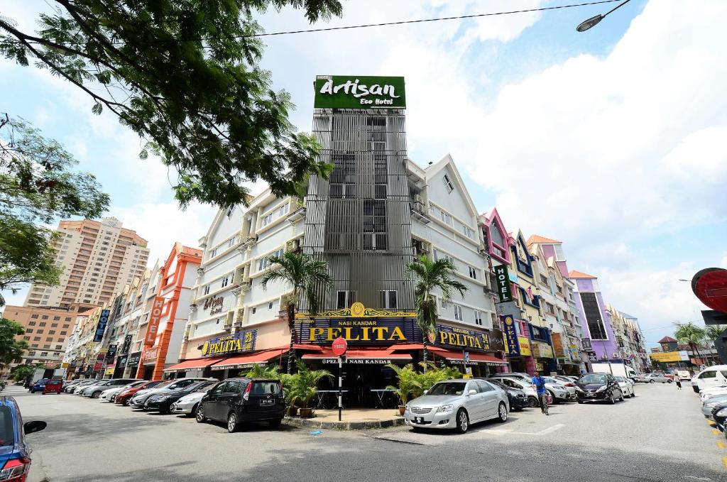 a building on a street with cars parked in a parking lot at Artisan Eco Hotel in Petaling Jaya