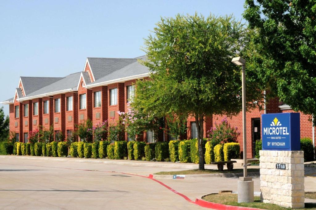 een rood bakstenen gebouw met een bord ervoor bij Microtel Inn & Suites by Wyndham Arlington/Dallas Area in Arlington