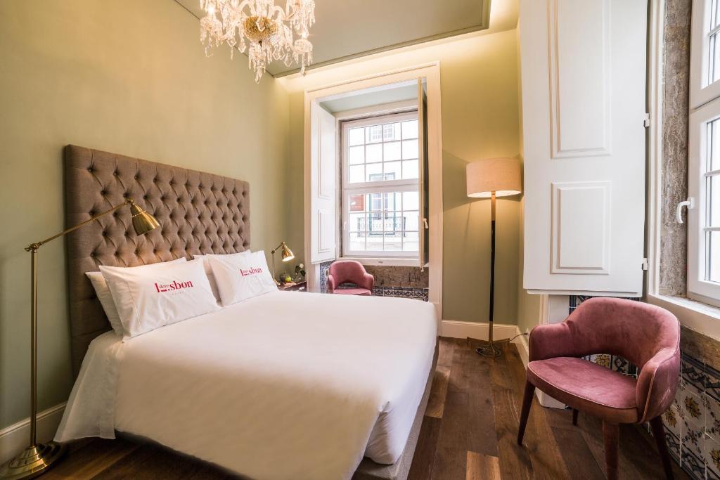 a bedroom with a large white bed and two chairs at Dare Lisbon House in Lisbon