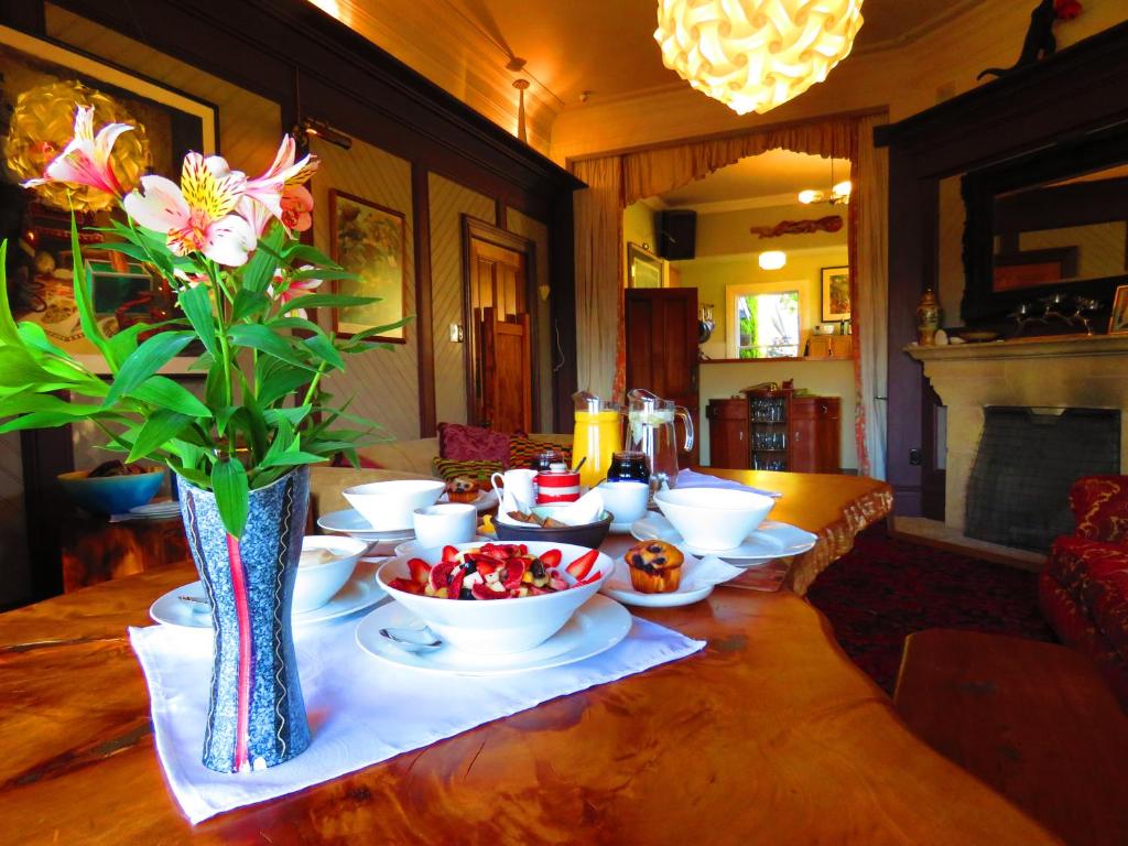 un tavolo con ciotole di frutta e un vaso con fiori di Shady Rest Bed & Breakfast a Takaka