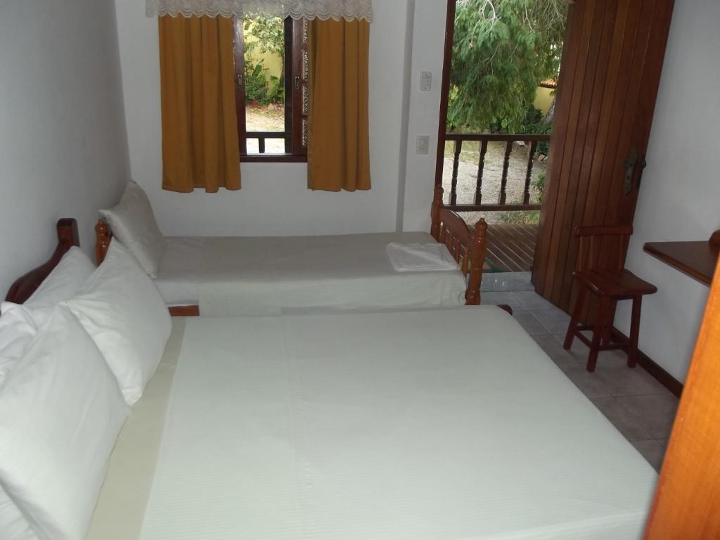 a bedroom with a white bed and two windows at Pousada Flats Paguru in Búzios