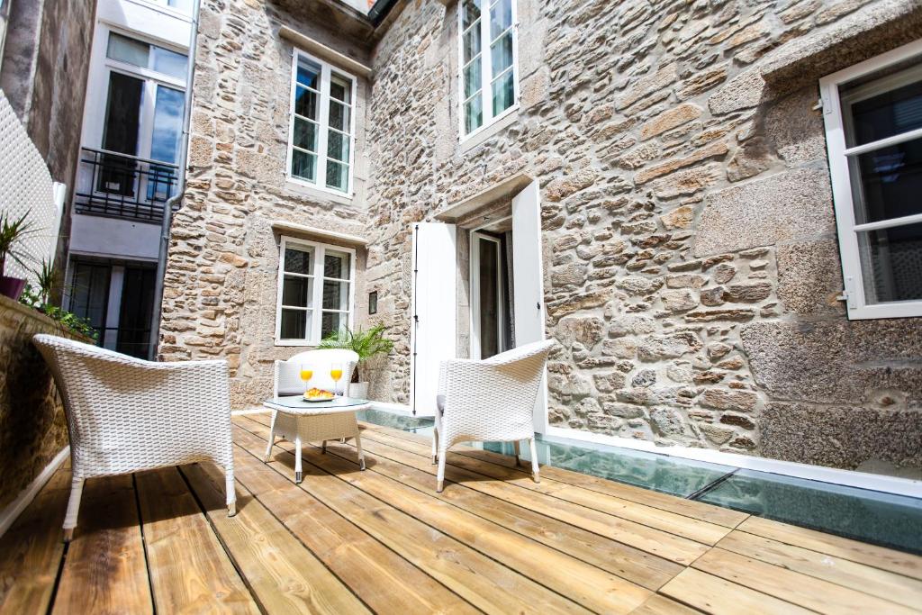 a wooden deck with two chairs and a building at Hotel Montenegro Compostela in Santiago de Compostela