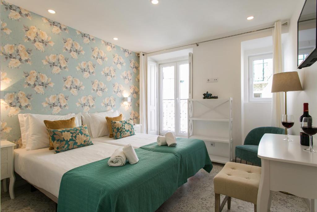 a bedroom with a white bed with green sheets and flowers at Suites Amália Guesthouse near Rossio Square in Lisbon