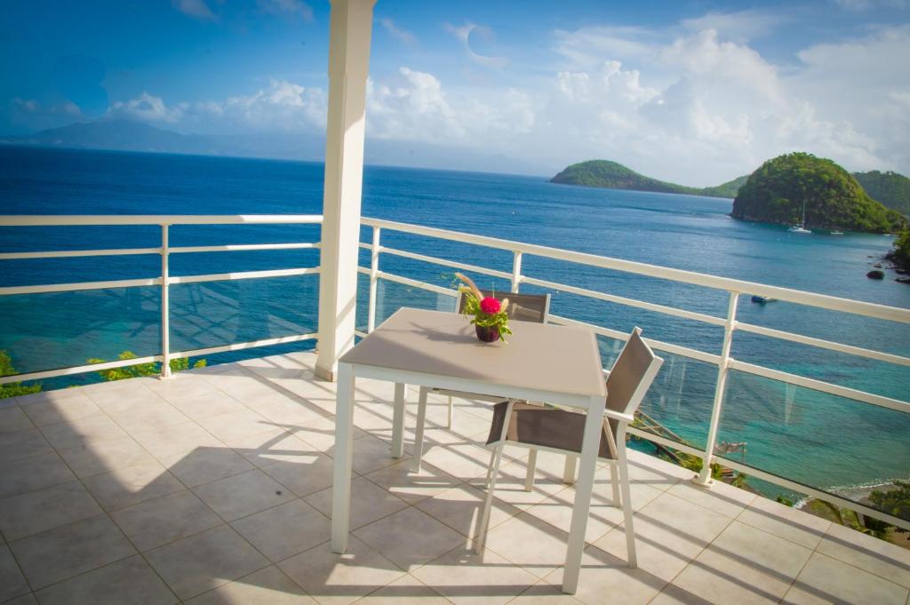 d'une table et de chaises blanches sur un balcon donnant sur l'océan. dans l'établissement Hôtel Bois Joli, à Terre-de-Haut