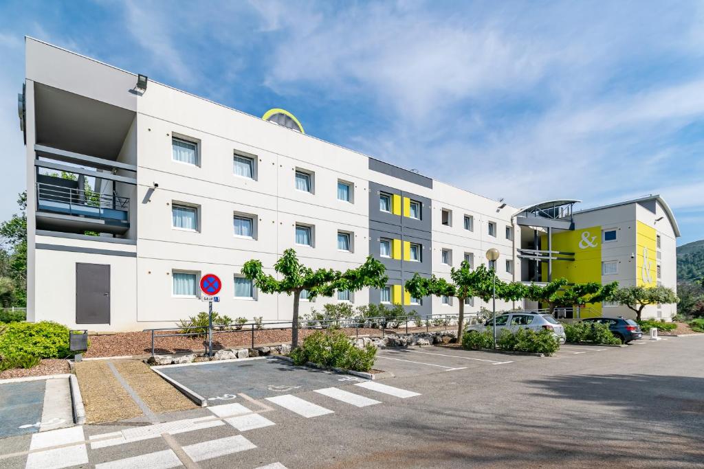 un gran edificio blanco con aparcamiento en B&B HOTEL Marseille La Valentine, en Marsella