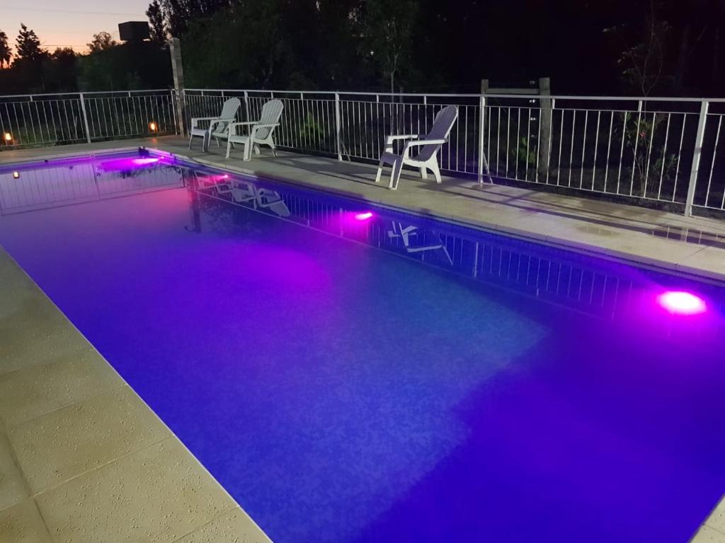 a swimming pool with purple lights in the night at Los manzanos . in Colón