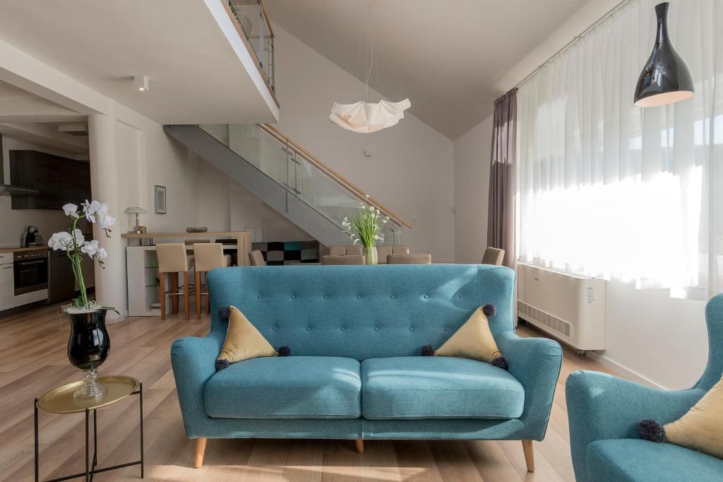 sala de estar con sofá azul y 2 sillas en Millennium apartments, en Čakovec