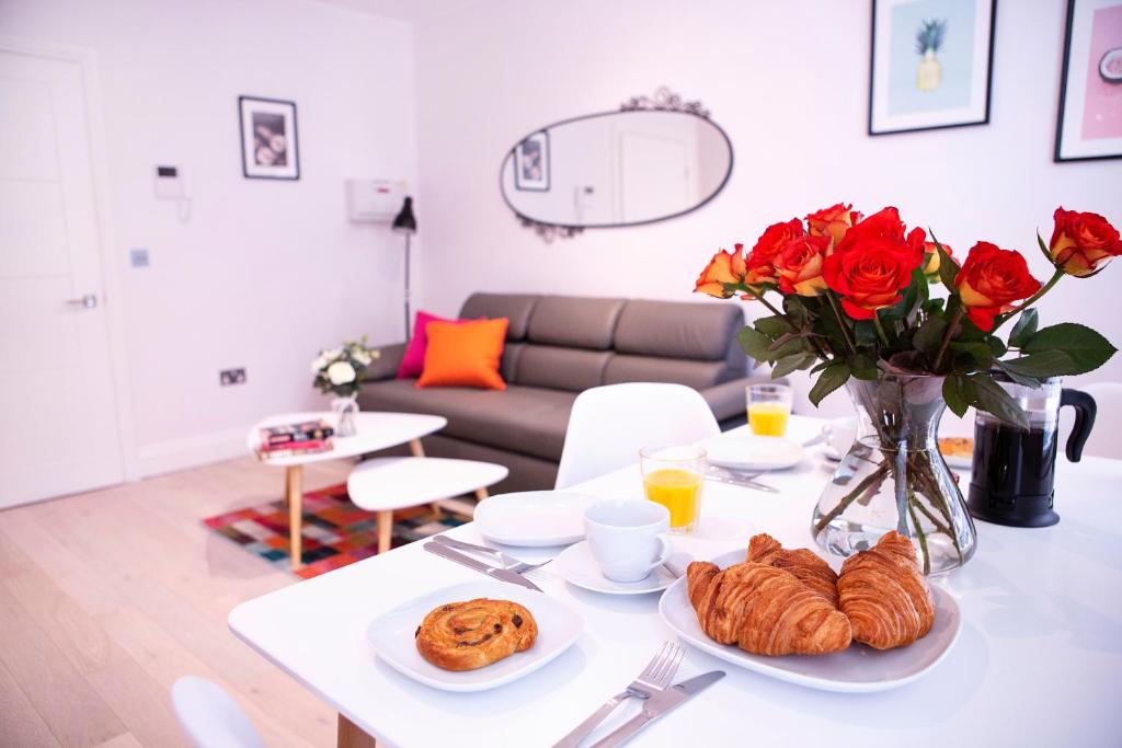 a living room with a table with roses and croissants at Quiet Central West End Apartments by Indigo Flats in London