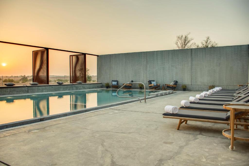 una piscina con una fila di sedie a sdraio accanto ad essa di Al Faya Retreat by Sharjah Collection a Sharjah