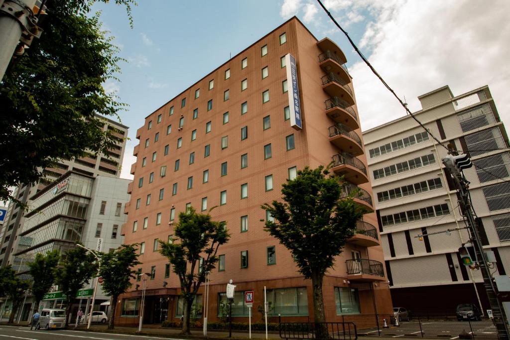 a building on a city street with buildings at Sanco Inn Kuwana Ekimae in Kuwana